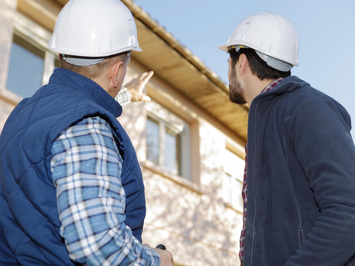 Two men talking and looking at the exterior of a house