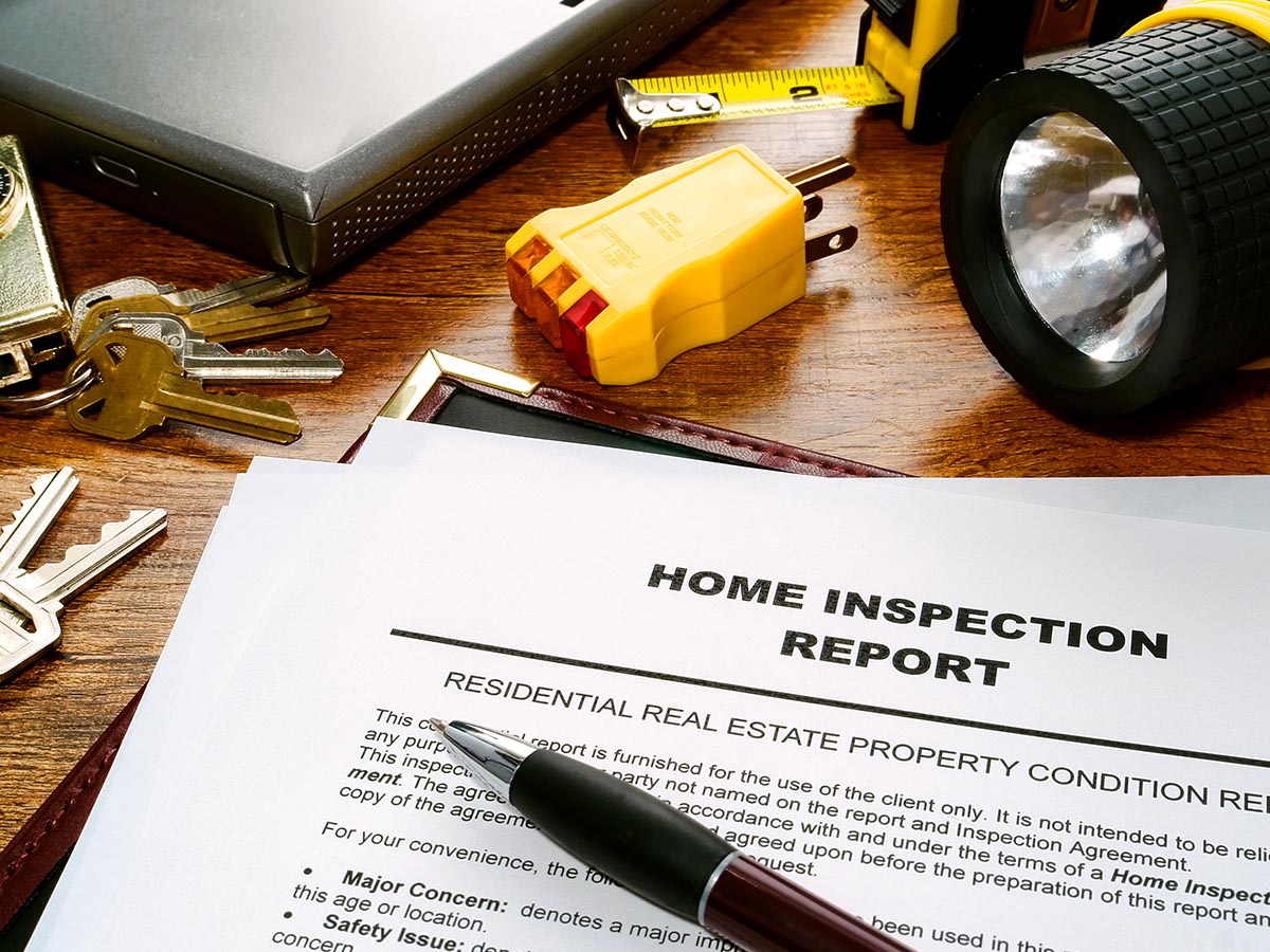 Home inspection report letter laying on a wood table next to house keys